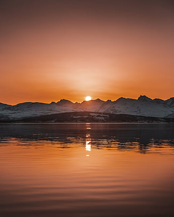 Stunning orange sunset over tranquil lake with mountain silhouette, perfect for serene . HD phone wallpaper