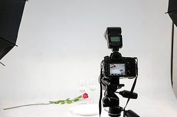 Camera setup in a graphy studio capturing a rose and wine glasses. HD wallpaper