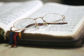 Close-up of eyeglasses atop an open Bible with colorful bookmarks, ideal for religious study themes. HD wallpaper