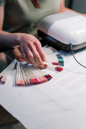 Close-up of a manicurist selecting nail polish colors in a salon setting. HD phone wallpaper