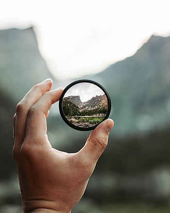 A stunning mountain landscape magnified through a handheld lens highlighting exploration and adventure. HD phone wallpaper