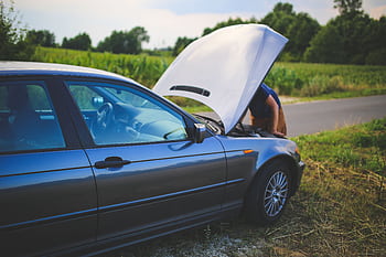 Man checking car engine with hood open by the side of a rural road. HD wallpaper