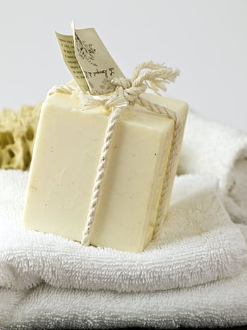A close-up of handmade soap wrapped with natural rope on white towels, ideal for spa or relaxation themes. HD phone wallpaper