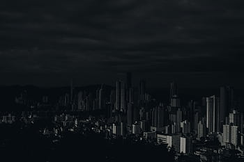 Dark and moody cityscape showcasing skyscrapers under a cloudy sky. HD wallpaper