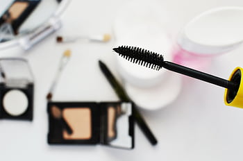 Flat lay of cosmetics featuring a mascara brush, perfect for beauty and fashion themes. HD wallpaper