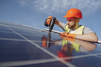Engineer in hard hat and safety gear installing solar panel outdoors. HD wallpaper