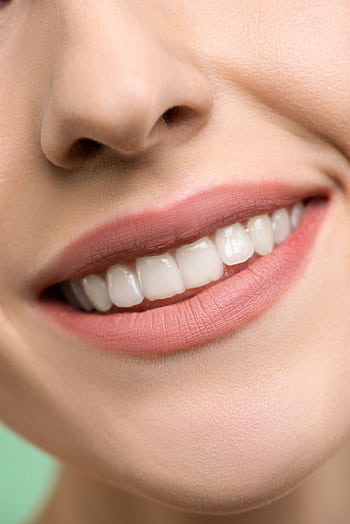 A close-up focusing on a woman's smiling mouth, showing white teeth and pink lips. HD phone wallpaper