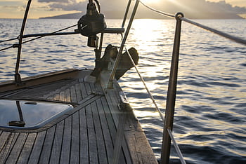 Experience serene sailing at sunset aboard a yacht navigating open waters. HD wallpaper
