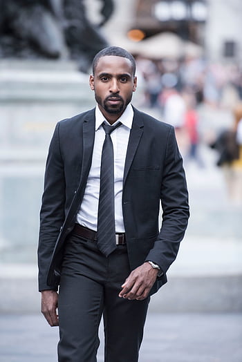 Confident businessman in a designer suit walking in an urban setting. HD phone wallpaper