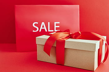 Gift box with red ribbon on red background with sale sign, perfect for retail promotions. HD wallpaper