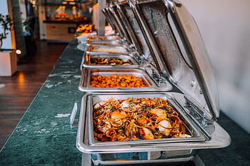 An elegant buffet setup featuring various delicious dishes in stainless steel chafing dishes, perfect for events. HD wallpaper