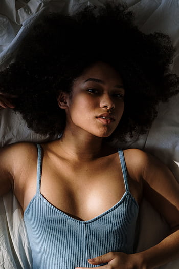 Beautiful woman with curly hair resting in bed, enjoying morning light. HD phone wallpaper
