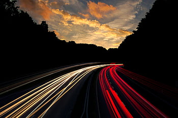 Dramatic long exposure of highway light trails beneath colorful twilight sky in Mönchengladbach, Germany. HD wallpaper