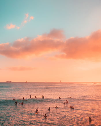 Surfers enjoy a breathtaking sunset at the beach in Honolulu, Hawaii, with vibrant sky colors. HD phone wallpaper