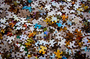 A close-up view of colorful jigsaw puzzle pieces scattered on a surface. HD wallpaper