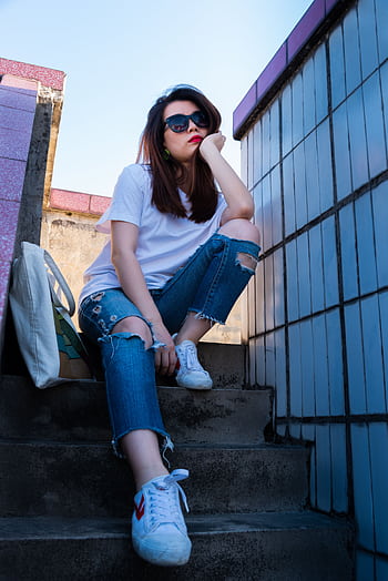 A stylish woman in sunglasses and casual attire sits thoughtfully on outdoor stairs. HD phone wallpaper
