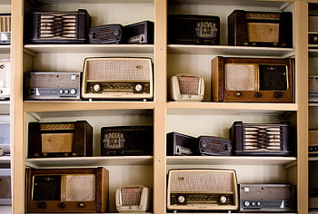 A curated collection of vintage radios displayed on shelves in an antique store, showcasing retro designs. HD wallpaper