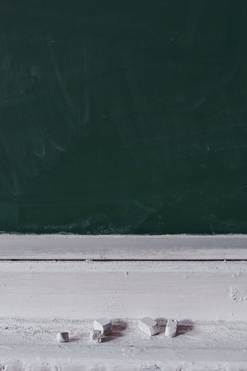 A dusty blackboard with chalk pieces, ideal for educational themes. HD phone wallpaper