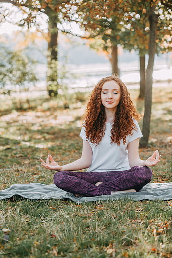 Woman meditating in a serene park during springtime, fostering relaxation and mental wellness. HD phone wallpaper