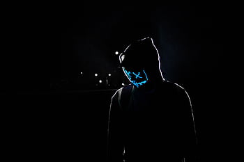 Silhouette of a person in a hoodie wearing a glowing LED mask against a dark background. HD wallpaper