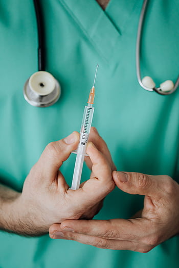 Doctor holding a syringe, ready for injection, with stethoscope. HD phone wallpaper