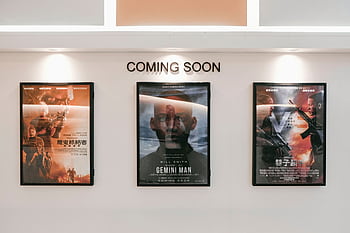 Framed posters of upcoming movies in a cinema hallway under 'Coming Soon' sign. HD wallpaper