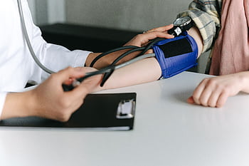 A healthcare worker uses a sphygmomanometer to check a patient's blood pressure in a medical office. HD wallpaper