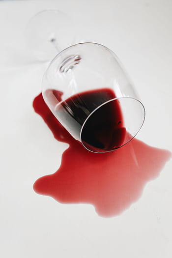 A spilled glass of red wine artfully displayed on a white surface, creating a dramatic contrast. HD phone wallpaper