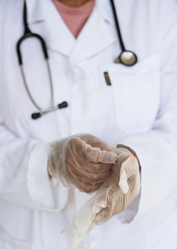 Close-up of a healthcare worker wearing sterile gloves with a stethoscope visible, symbolizing medical readiness. HD phone wallpaper
