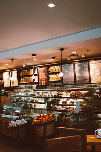 Warm and inviting café interior with a modern design, featuring a well-stocked counter and stylish lighting. HD phone wallpaper