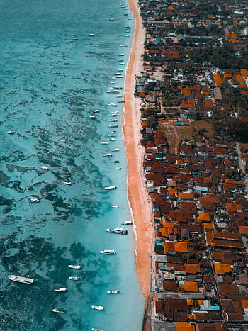 A scenic aerial view of the vibrant coast in Bali, showcasing the clear blue waters and nearby resorts. HD phone wallpaper