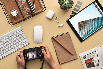 Overhead view of a modern workspace featuring tech gadgets, a camera, and a notepad. HD wallpaper