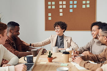 Business professionals engaged in a collaborative meeting in a modern office setting, sharing ideas and smiling. HD wallpaper