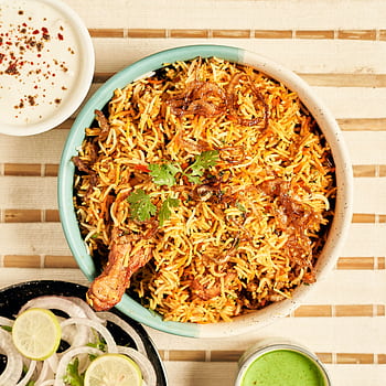 Delicious chicken biryani served with onion rings, lime, and yogurt dip, perfect for food lovers. HD phone wallpaper