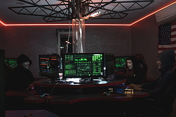 Team of hackers with Guy Fawkes masks coding in a dark room with computers. HD wallpaper