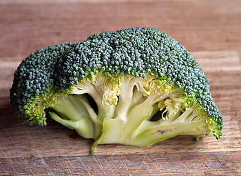 Fresh green broccoli close-up on a wooden cutting board, highlighting its texture. HD wallpaper