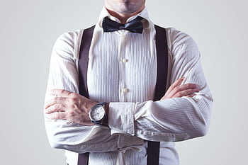 A stylish man crossing his arms, dressed elegantly in a bow tie and suspenders. HD wallpaper