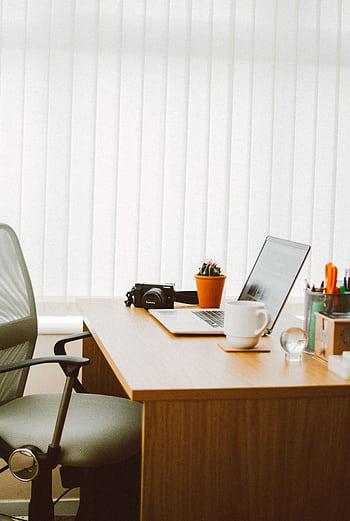 A clean and bright home office setup with a laptop, chair, and desk essentials. HD phone wallpaper