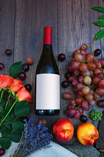 A vibrant display of wine, fresh grapes, peaches, and roses on a wooden surface. HD phone wallpaper