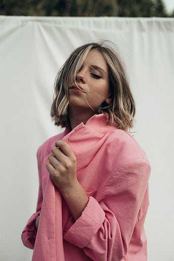 Young woman in a pink jacket outdoors, enjoying a serene moment with eyes closed. HD phone wallpaper