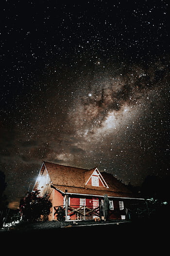 A captivating view of the Milky Way illuminating a rustic farmhouse under a starry night sky. HD phone wallpaper