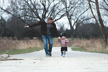 Dad and daughter enjoying a walk in the park, symbolizing love and togetherness. HD wallpaper