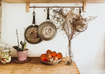A cozy, rustic kitchen setup with hanging pans and wooden decor in an organized interior space. HD wallpaper