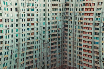 A modern high-rise building with a detailed view of multiple windows and balconies, showcasing urban architecture. HD wallpaper