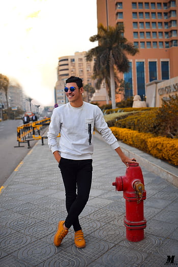 Young man posing by fire hydrant in vibrant cityscape HD phone wallpaper
