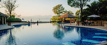 Serene resort pool with sunset views, ideal for relaxation and leisure travel. HD wallpaper