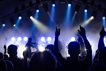 Silhouetted audience enjoying a live band performance with dramatic lighting at night. HD wallpaper