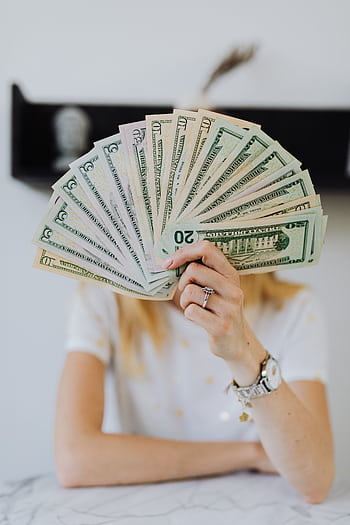 A person holding a fan of US dollar bills, symbolizing wealth and financial success. HD phone wallpaper