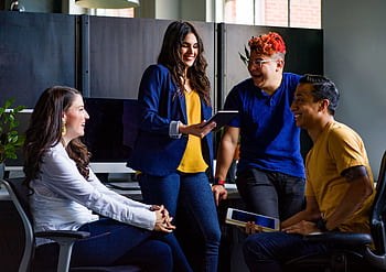 A diverse group of coworkers engaging in a lively discussion in a stylish office environment. HD wallpaper