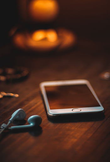 Mobile with ears on a wooden table in warm ambient light, creating a cozy atmosphere. HD phone wallpaper
